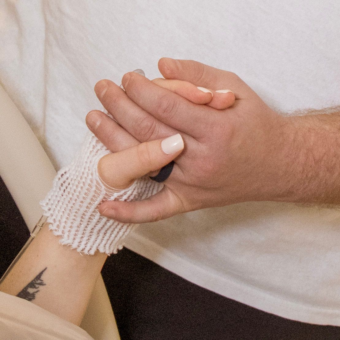 Close-up of hands clasped together with medical identification bracelet visible.