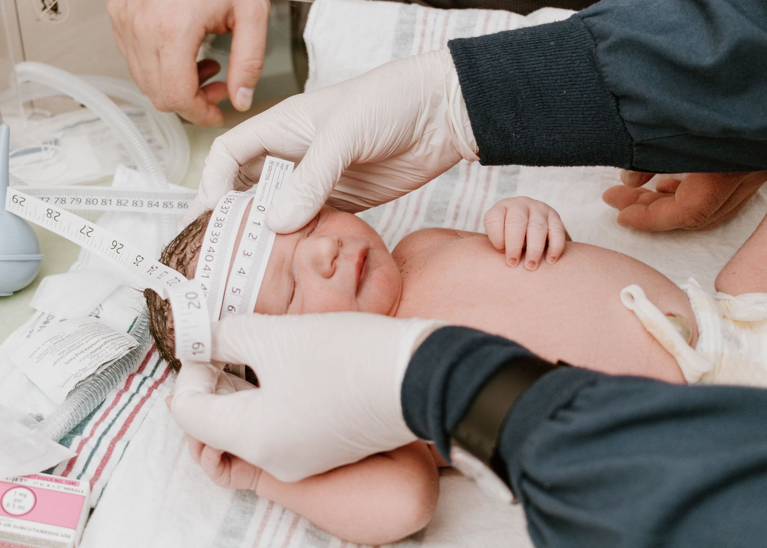 Medical professional measuring newborn baby during health checkup.