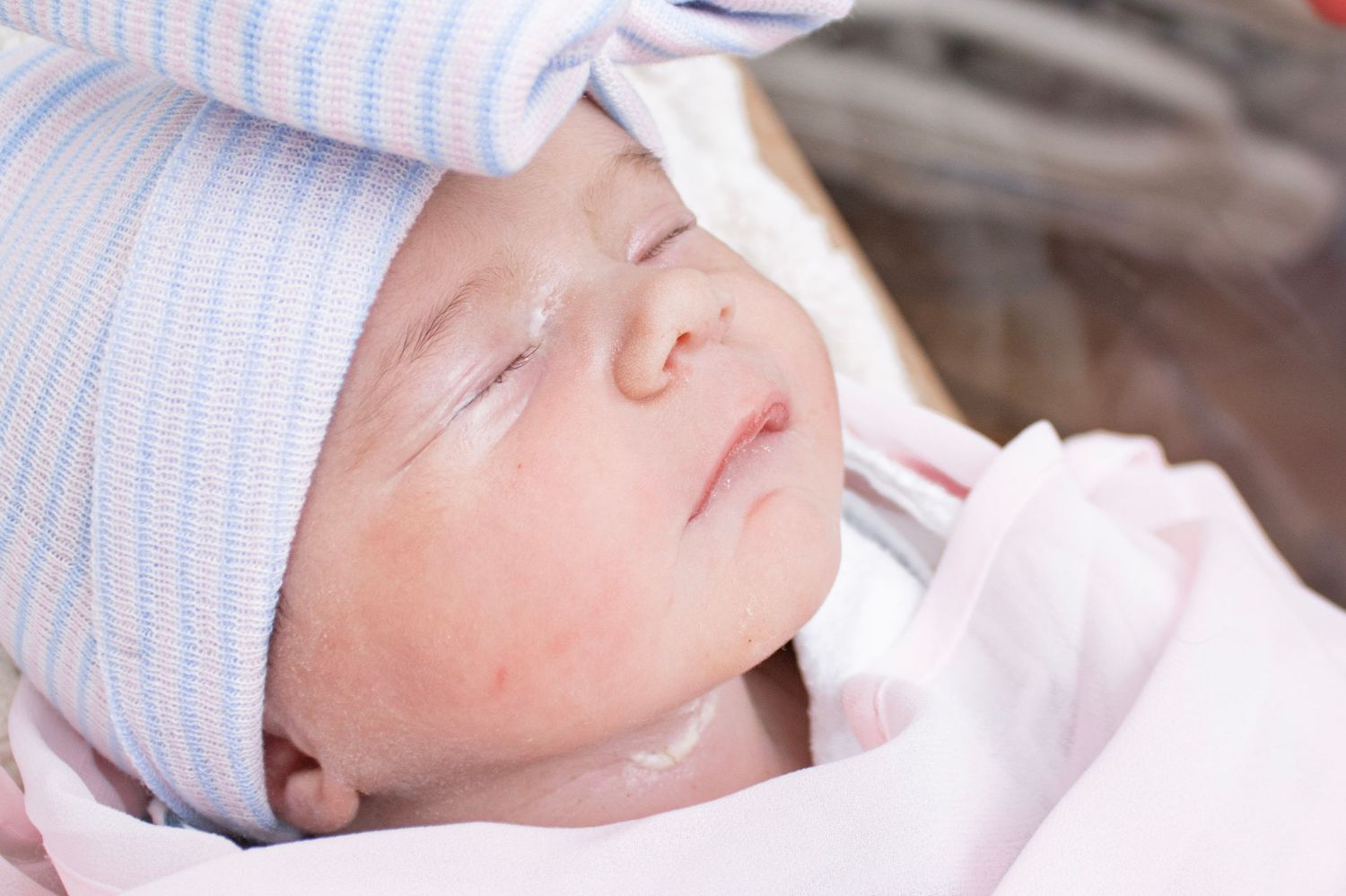 Sleeping newborn baby wearing a blue and white striped hat.