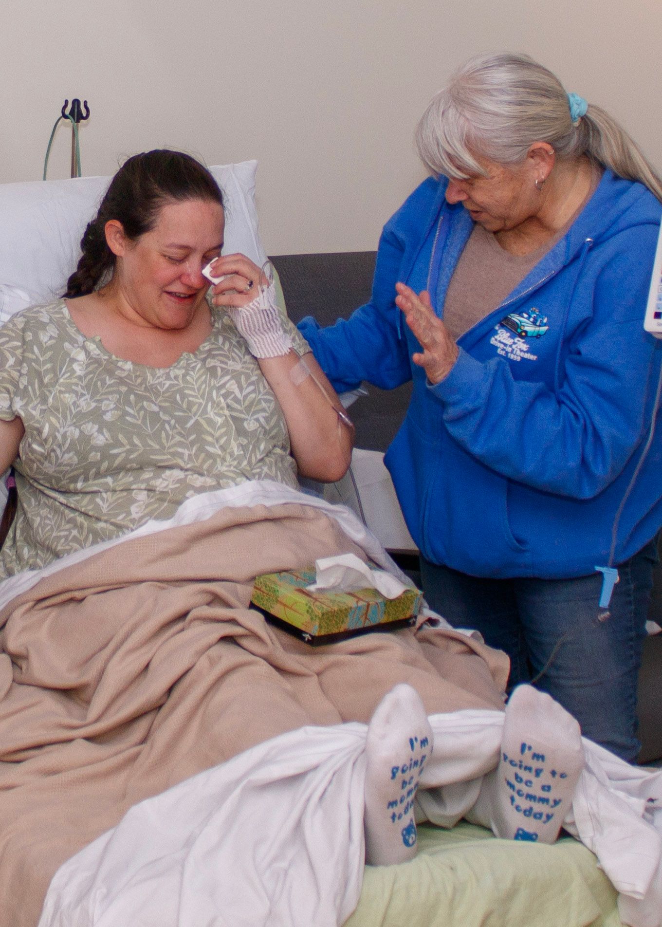 Emotional moment shared between two individuals in a hospital room with cozy blankets.