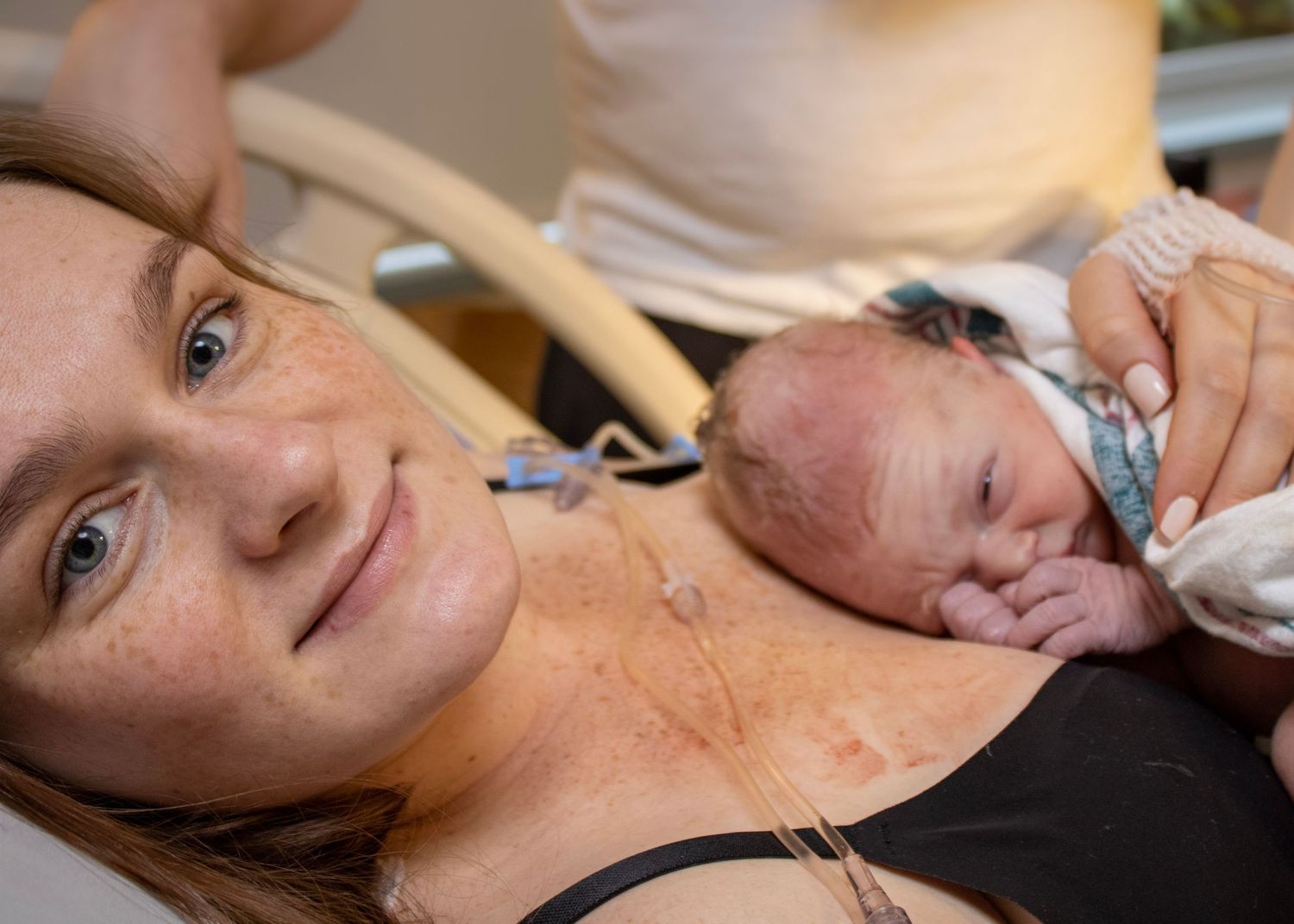 A newborn baby rests on parent's chest during first moments after birth.