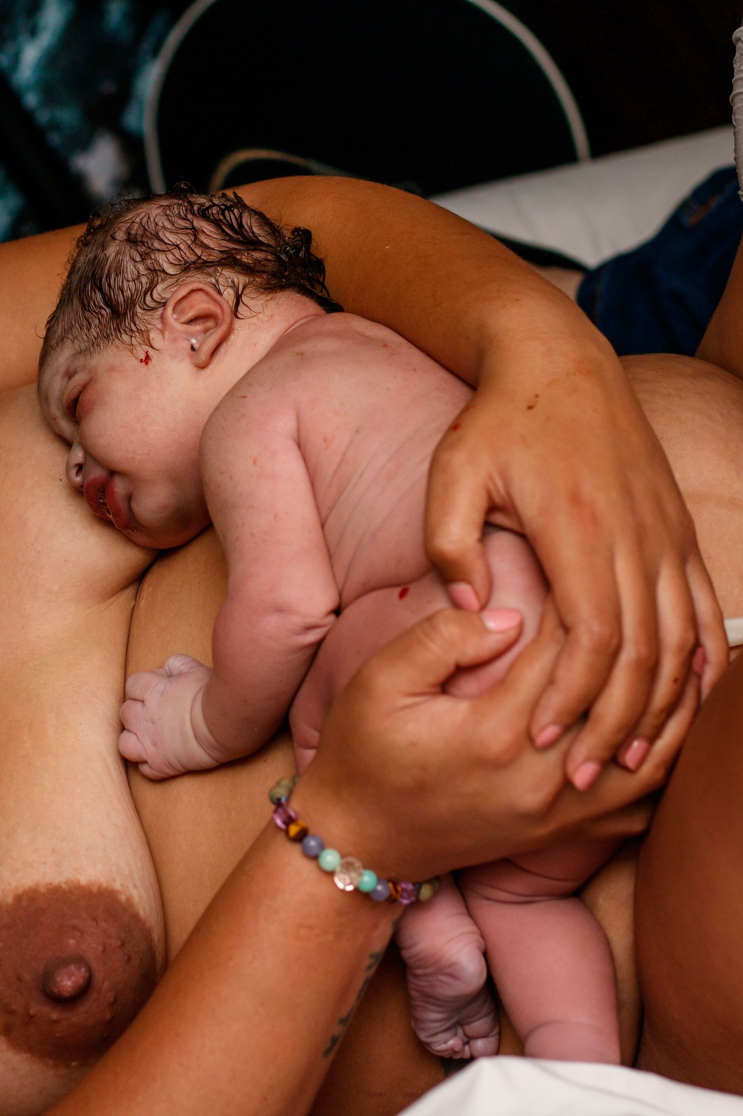 Newborn baby rests peacefully on parent's chest during skin-to-skin contact after birth.