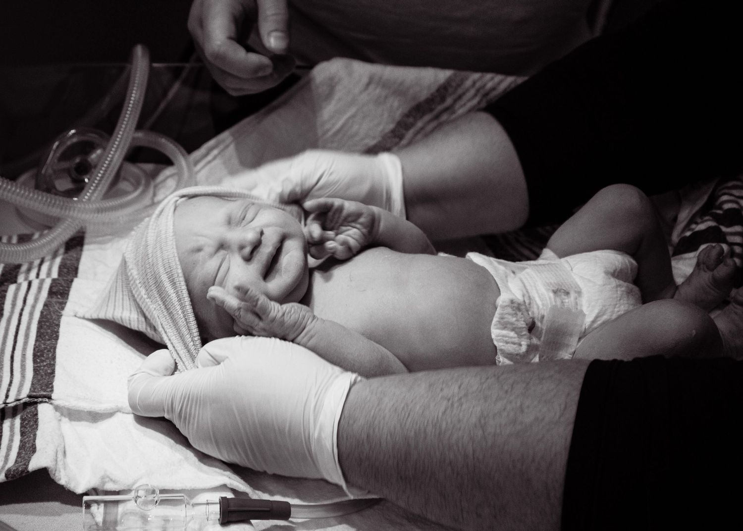 Black and white image showing medical staff attending to a newborn delivery.