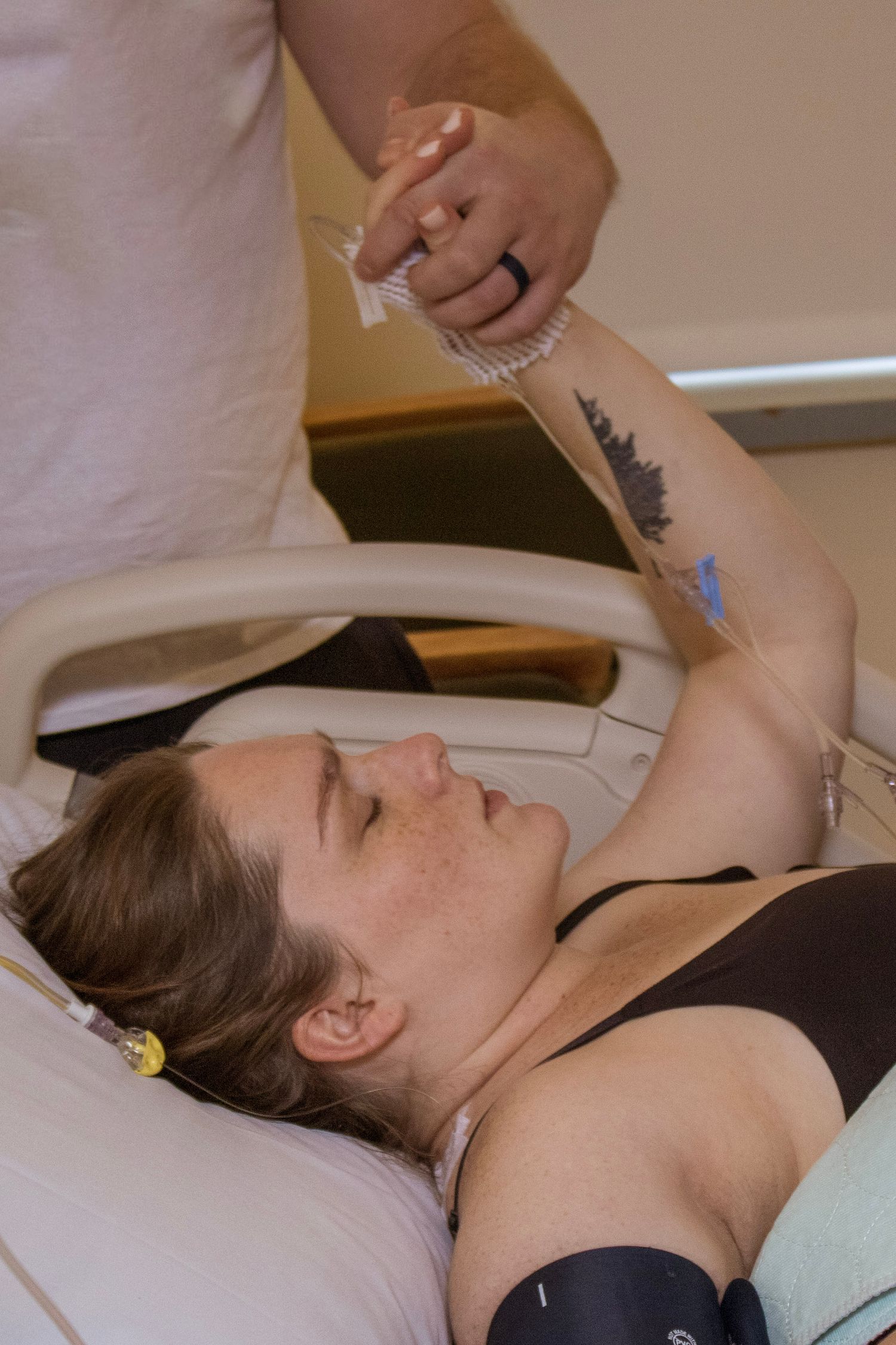 Someone rests in a hospital bed while receiving medical support during labor.