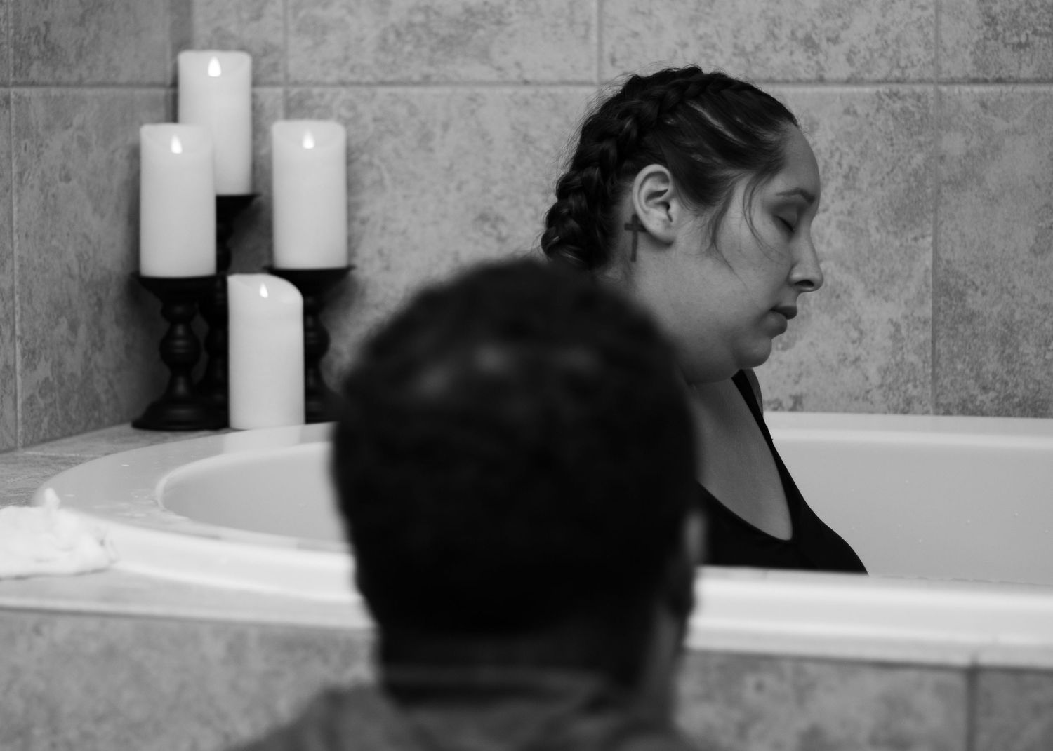 Black and white photo of intimate water birth preparation with candles in background.
