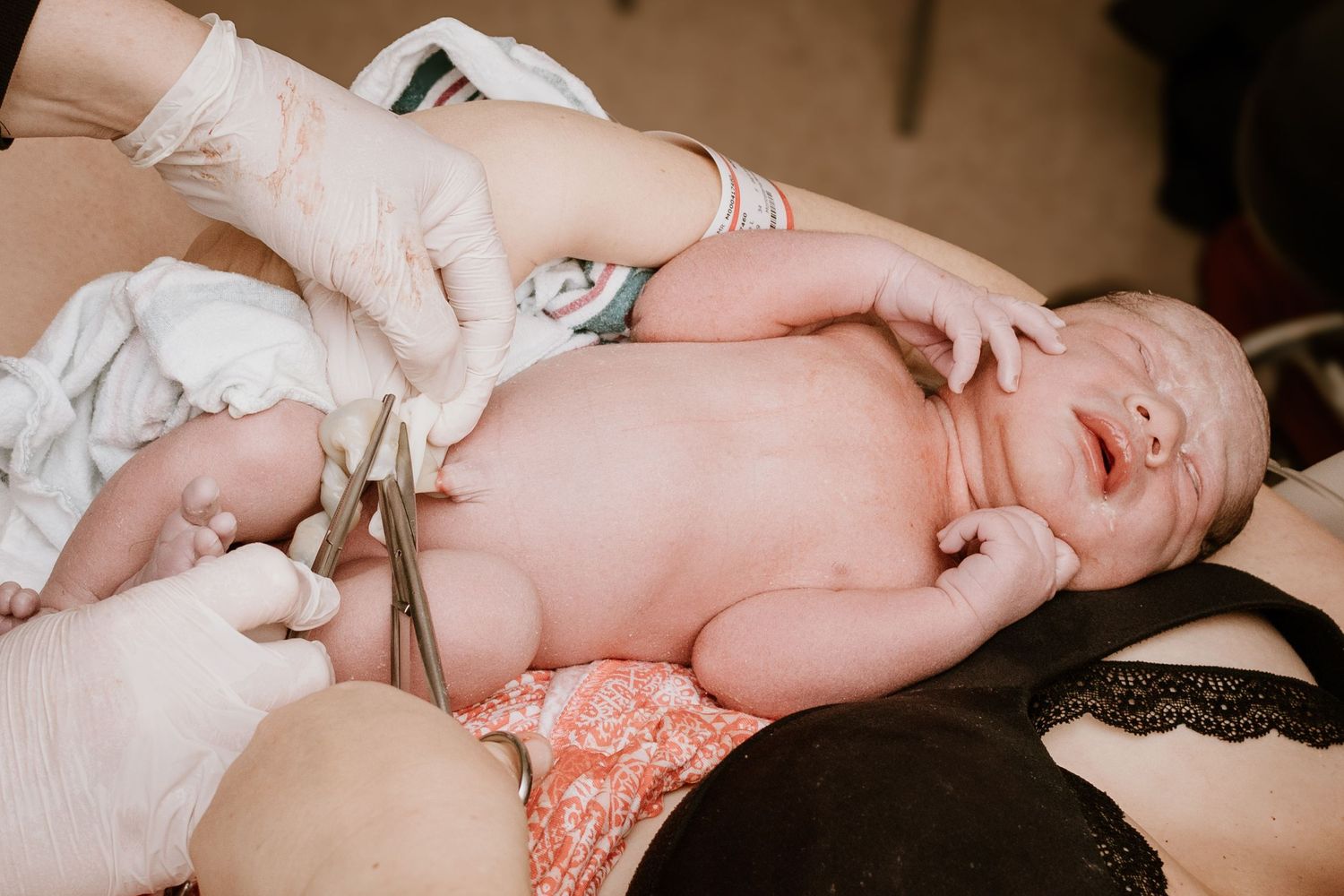 Medical staff examining newborn baby after delivery in hospital room.