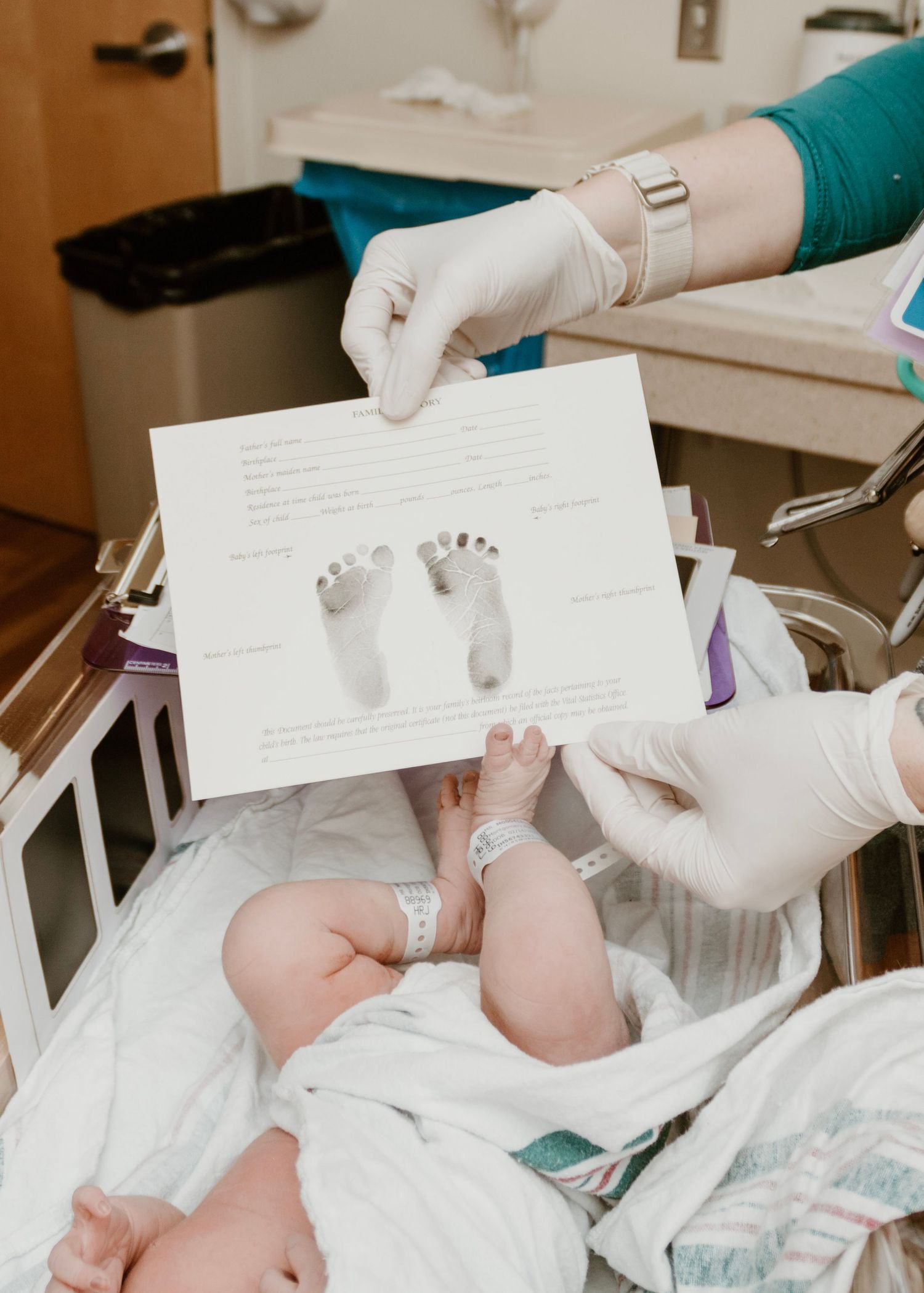 Medical staff taking footprints of newborn baby in hospital.