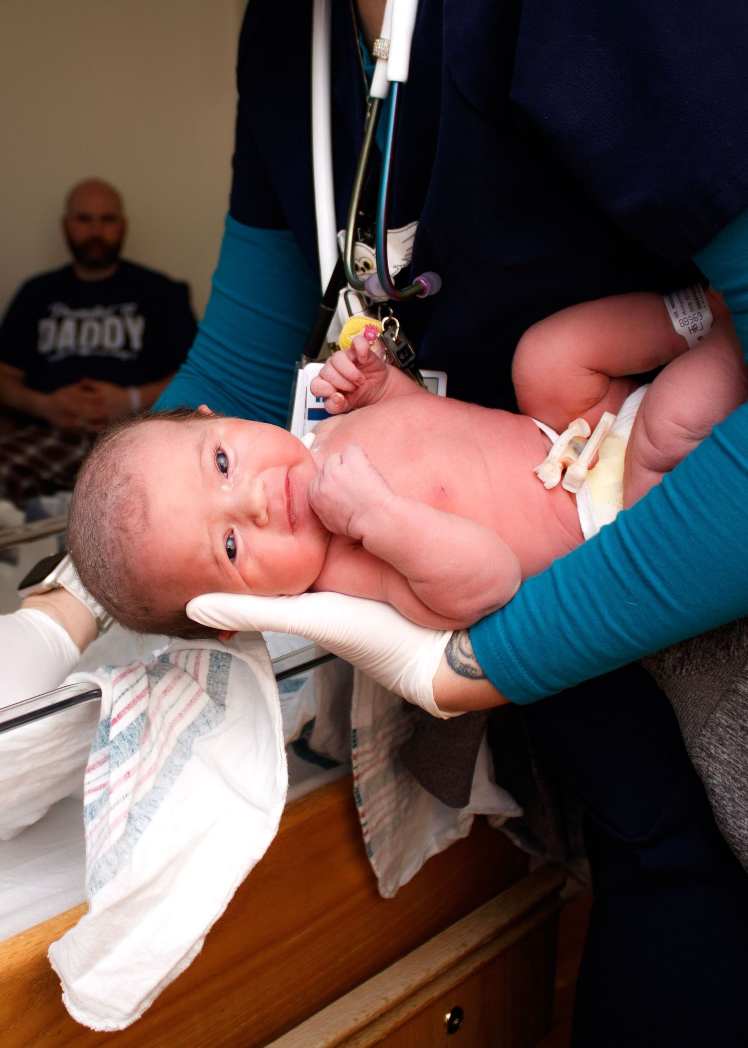 Medical professional examining newborn baby on examination table.