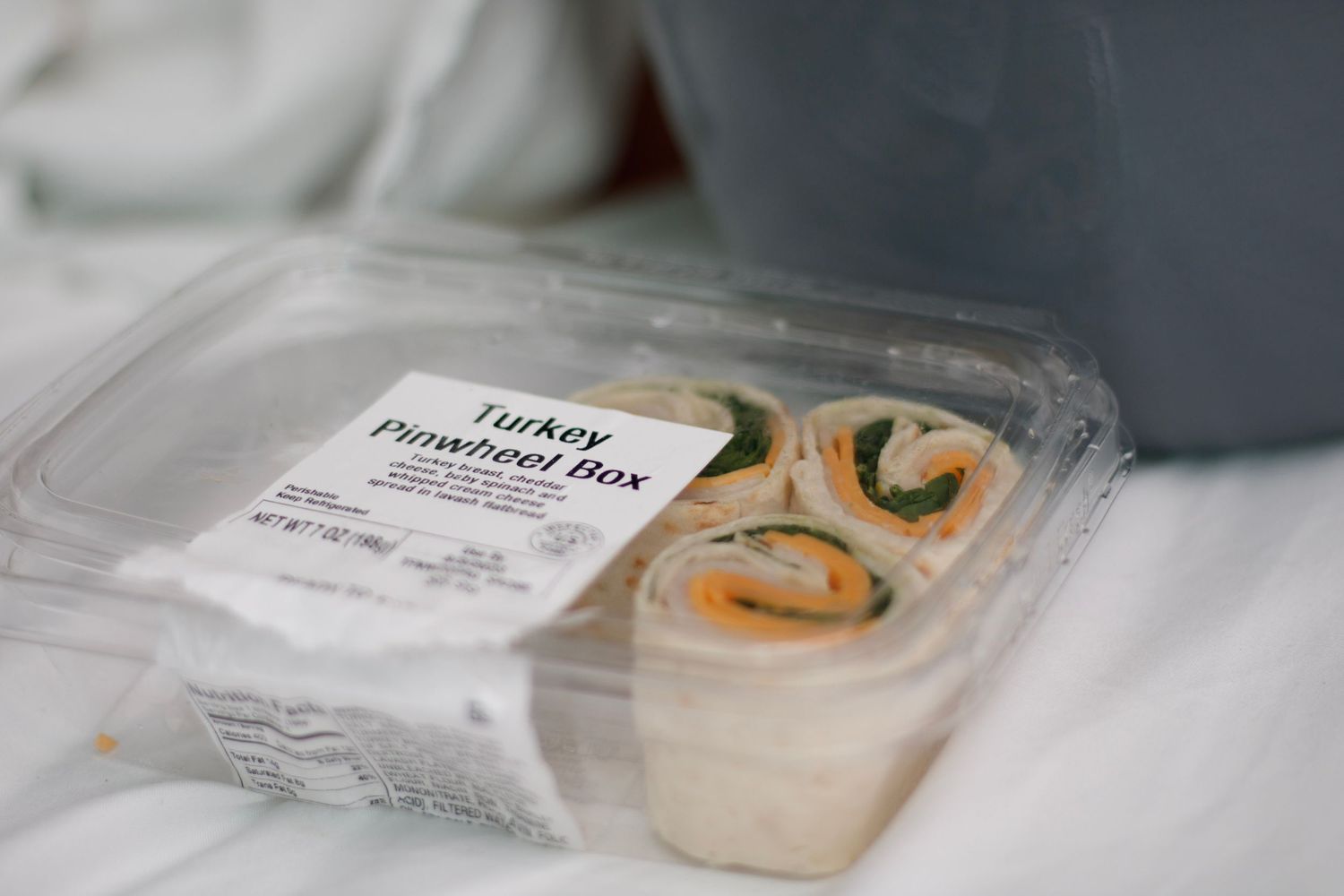 Packaged turkey sandwich in clear plastic container on white surface.