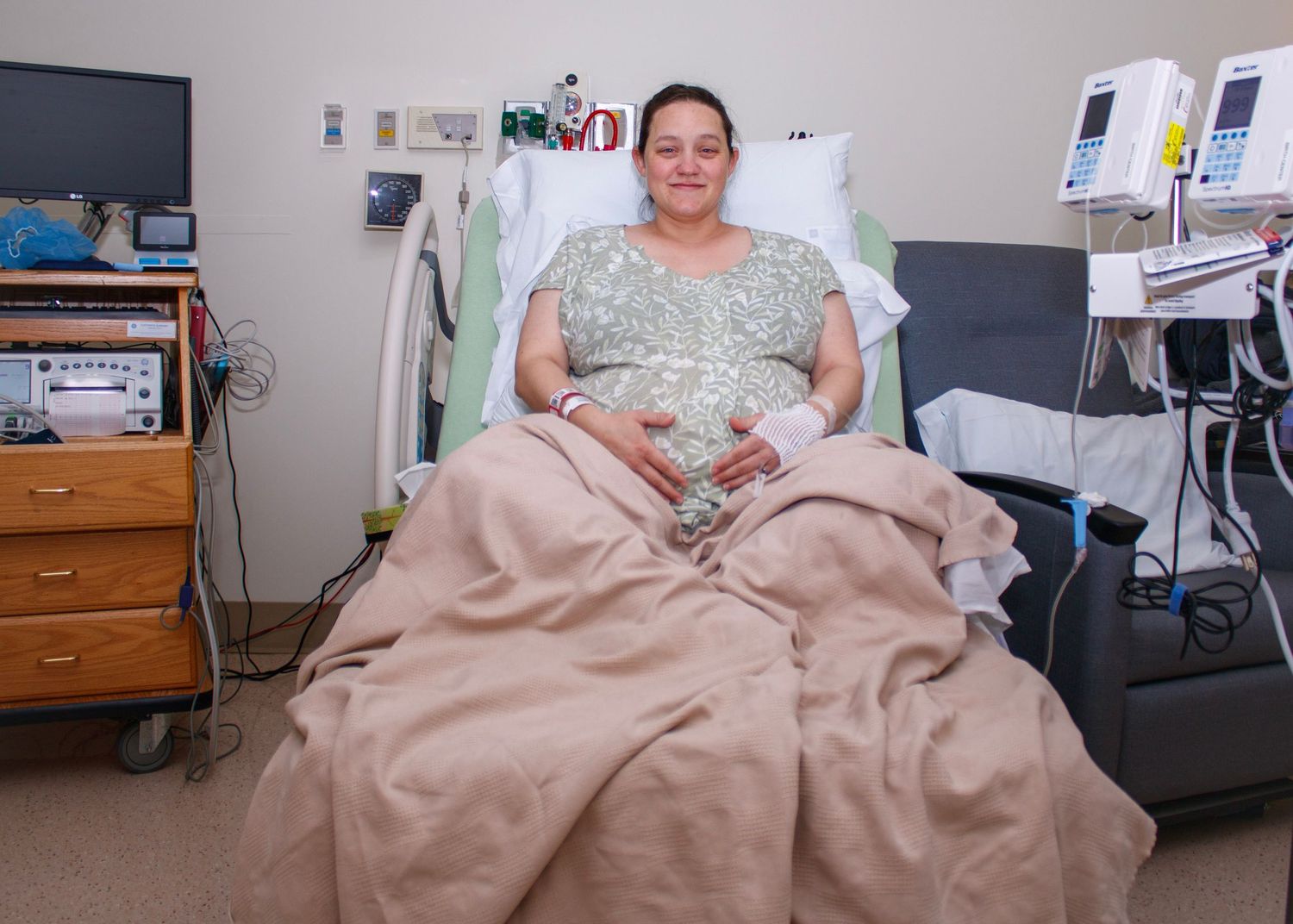 Patient resting in hospital bed with medical equipment in background.