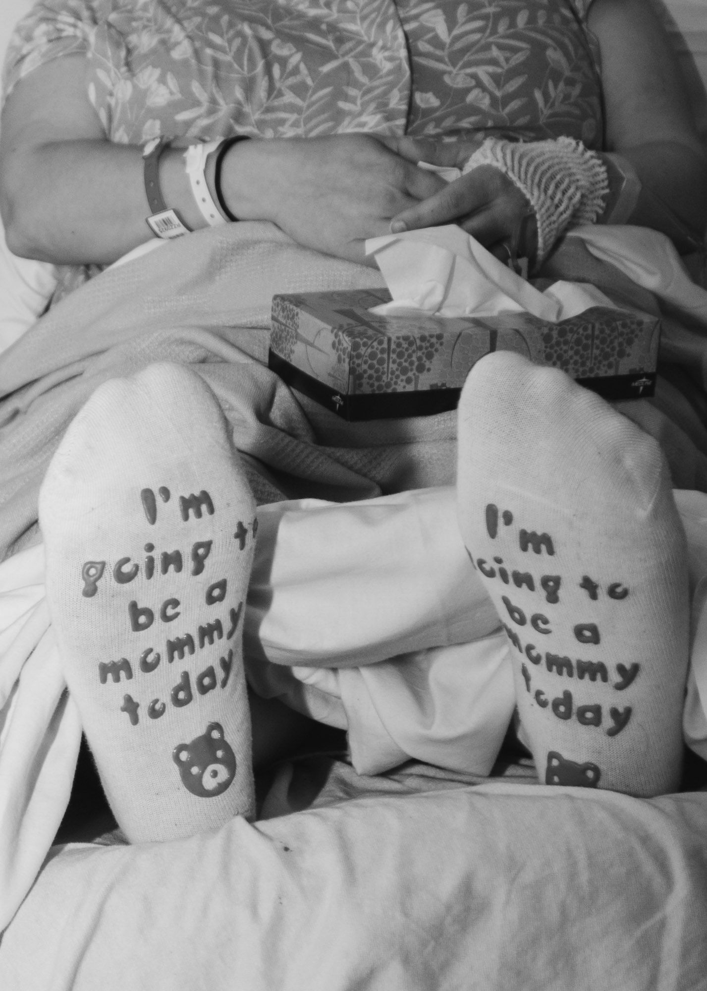 Hospital socks with message about becoming a mommy displayed on bed.