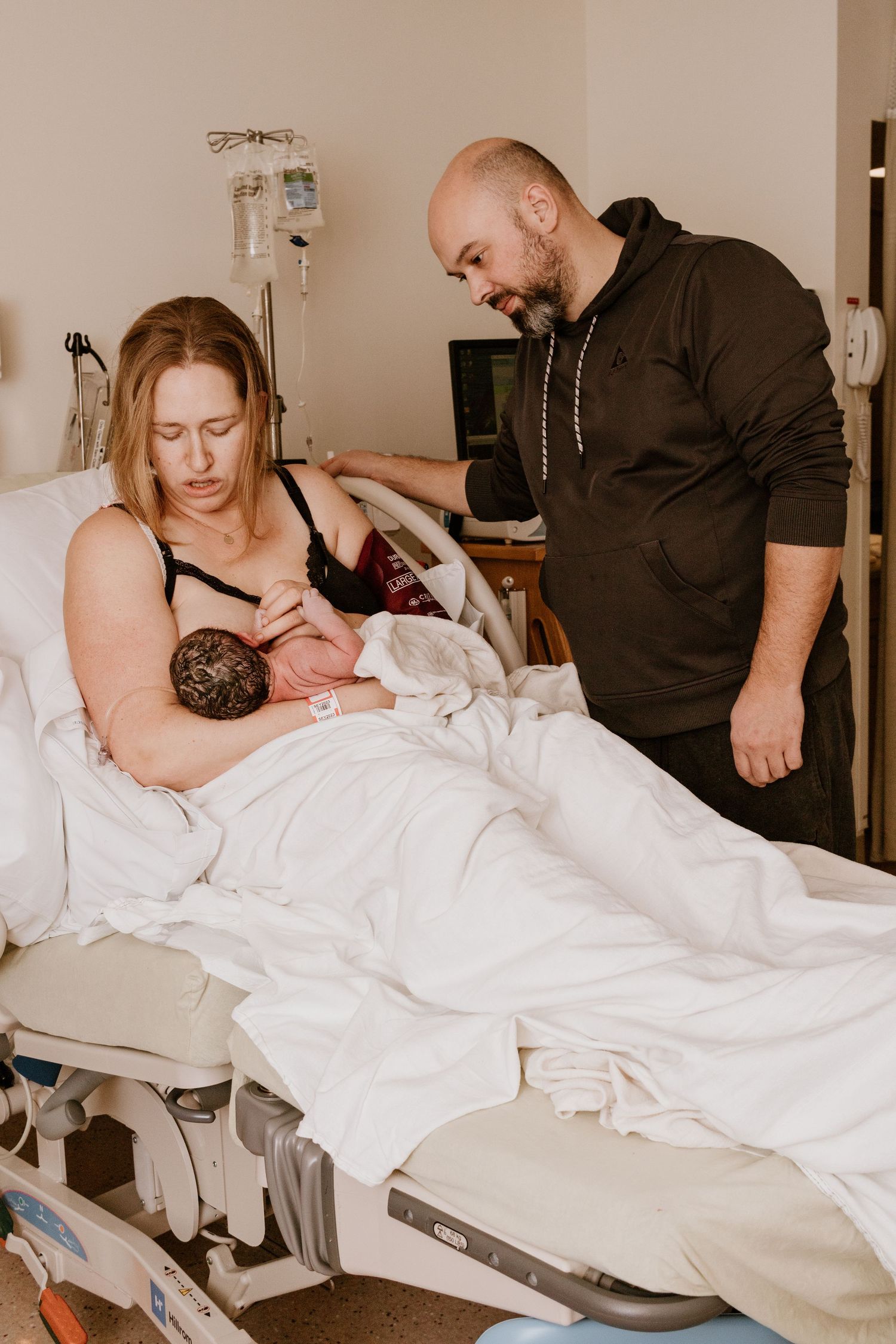 Hospital room scene showing new parents bonding with newborn baby after delivery.