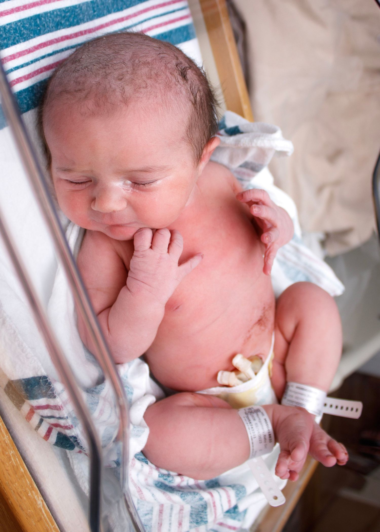 Newborn baby lying on medical examination table wearing diaper.