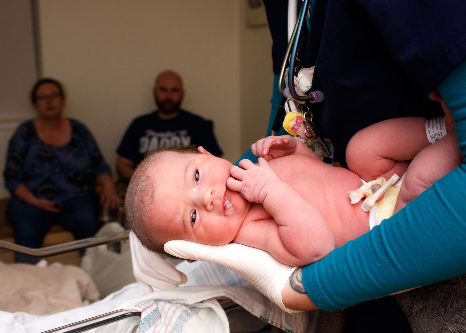Newborn baby being examined by medical staff in hospital delivery room.