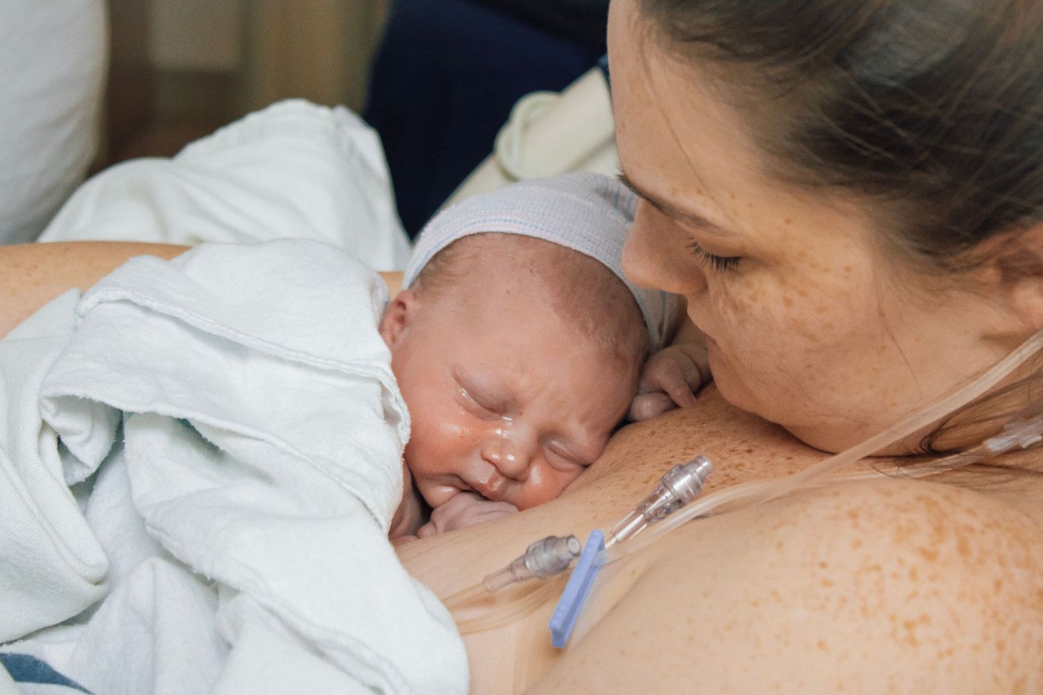 Tender moment between mother and newborn baby in hospital setting.