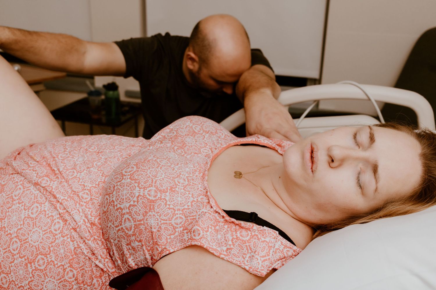 Medical examination taking place in a hospital room with pink patient gown.