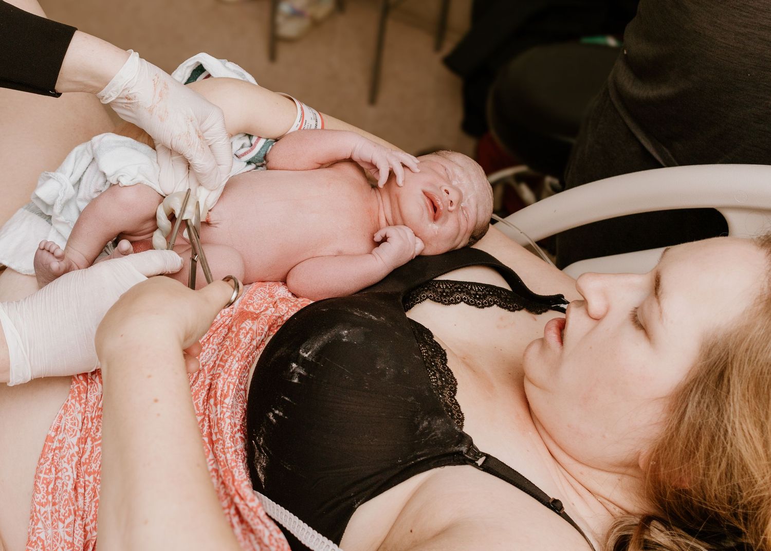 A newborn baby being examined by medical staff in a delivery room.
