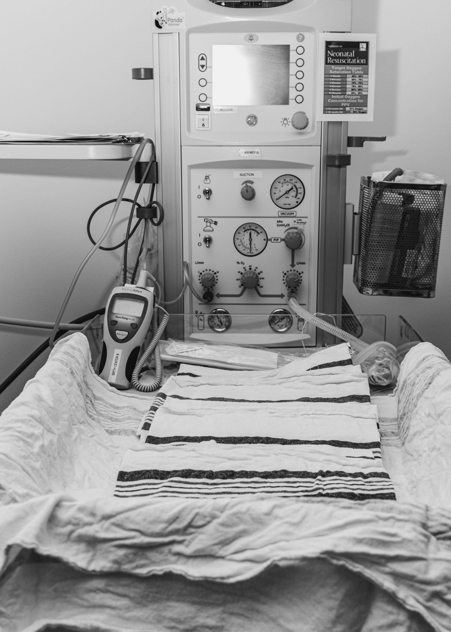 Medical equipment and monitoring devices set up in a hospital room with white bedding.