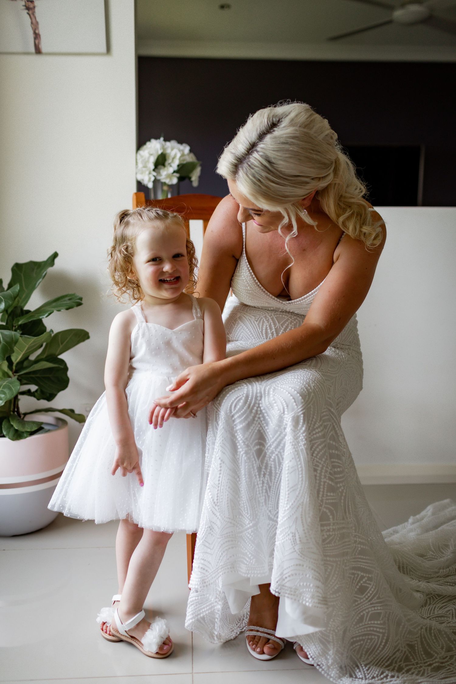 Sweet moment between two people in white dresses during wedding preparations.