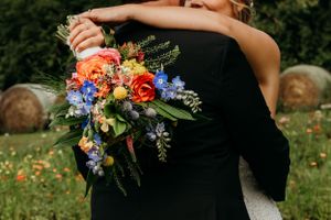 Bride is holding a bouquet of flowers with her arms around the grooms neck.