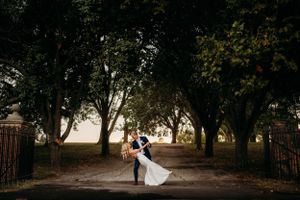 Groom dips the bride in an open drive way at sunset.