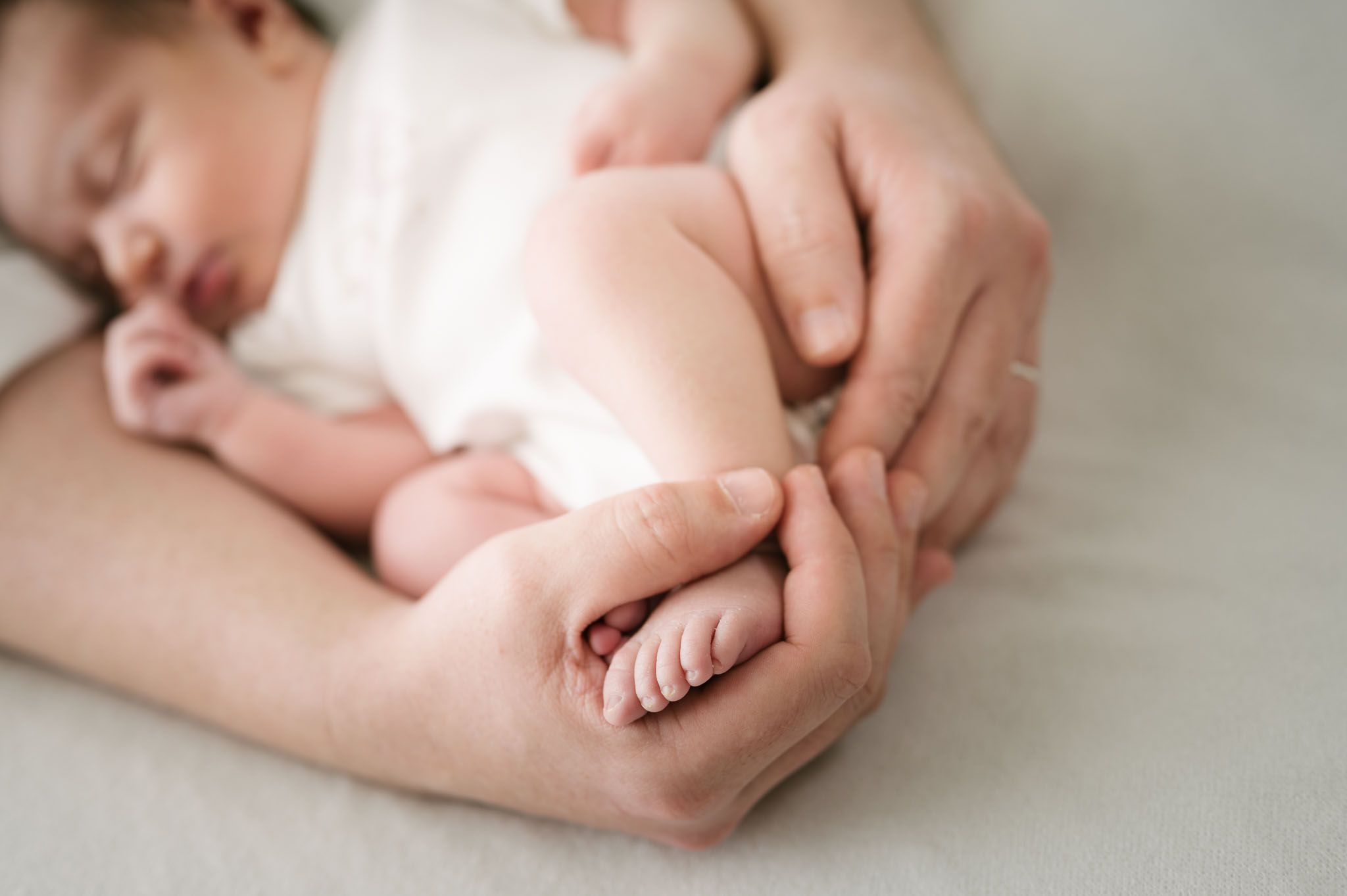 Close-up photo of tiny newborn baby feet being held in gentle hands.