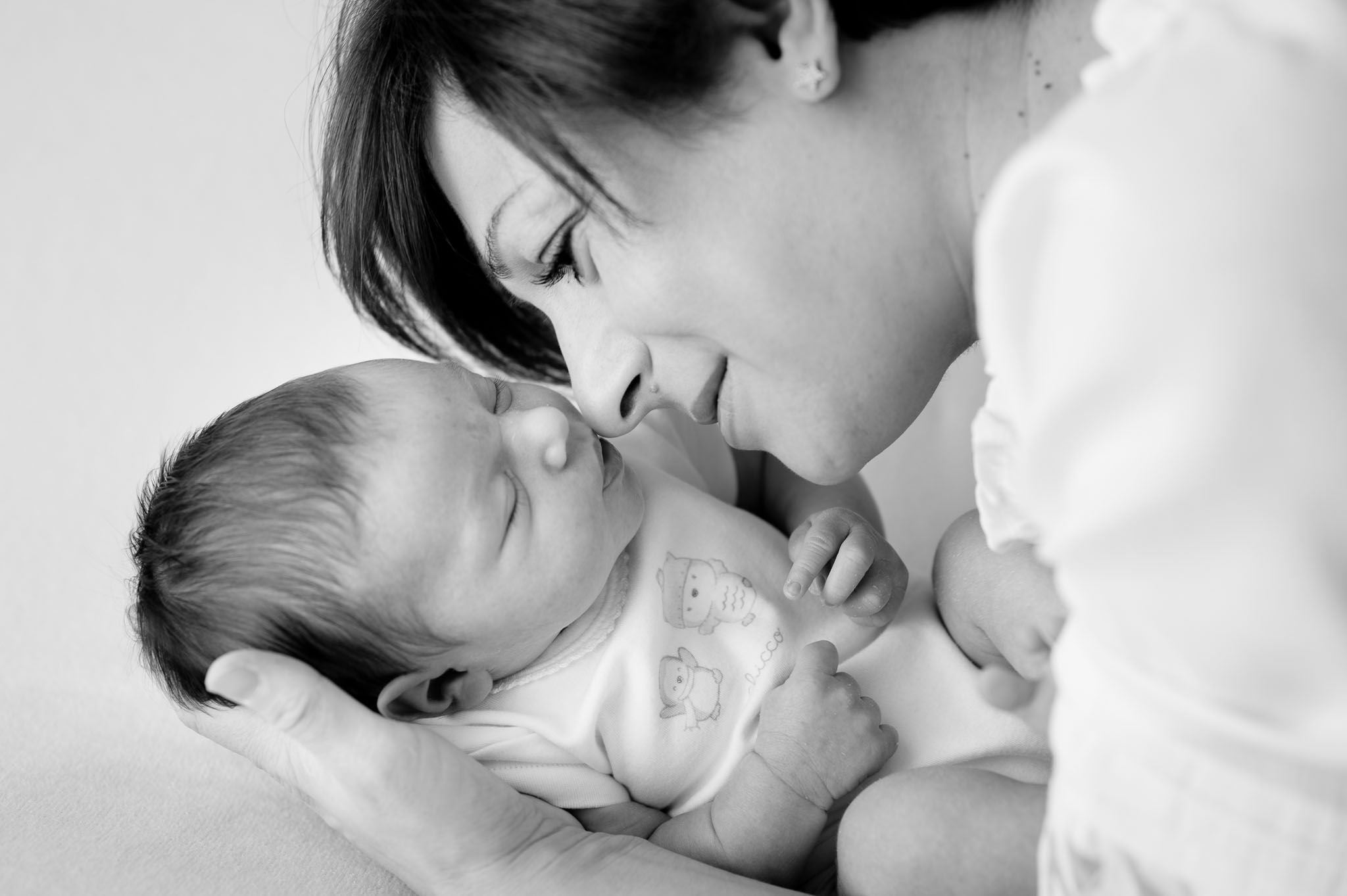 Intimate black and white portrait of tender moment between mother and newborn.