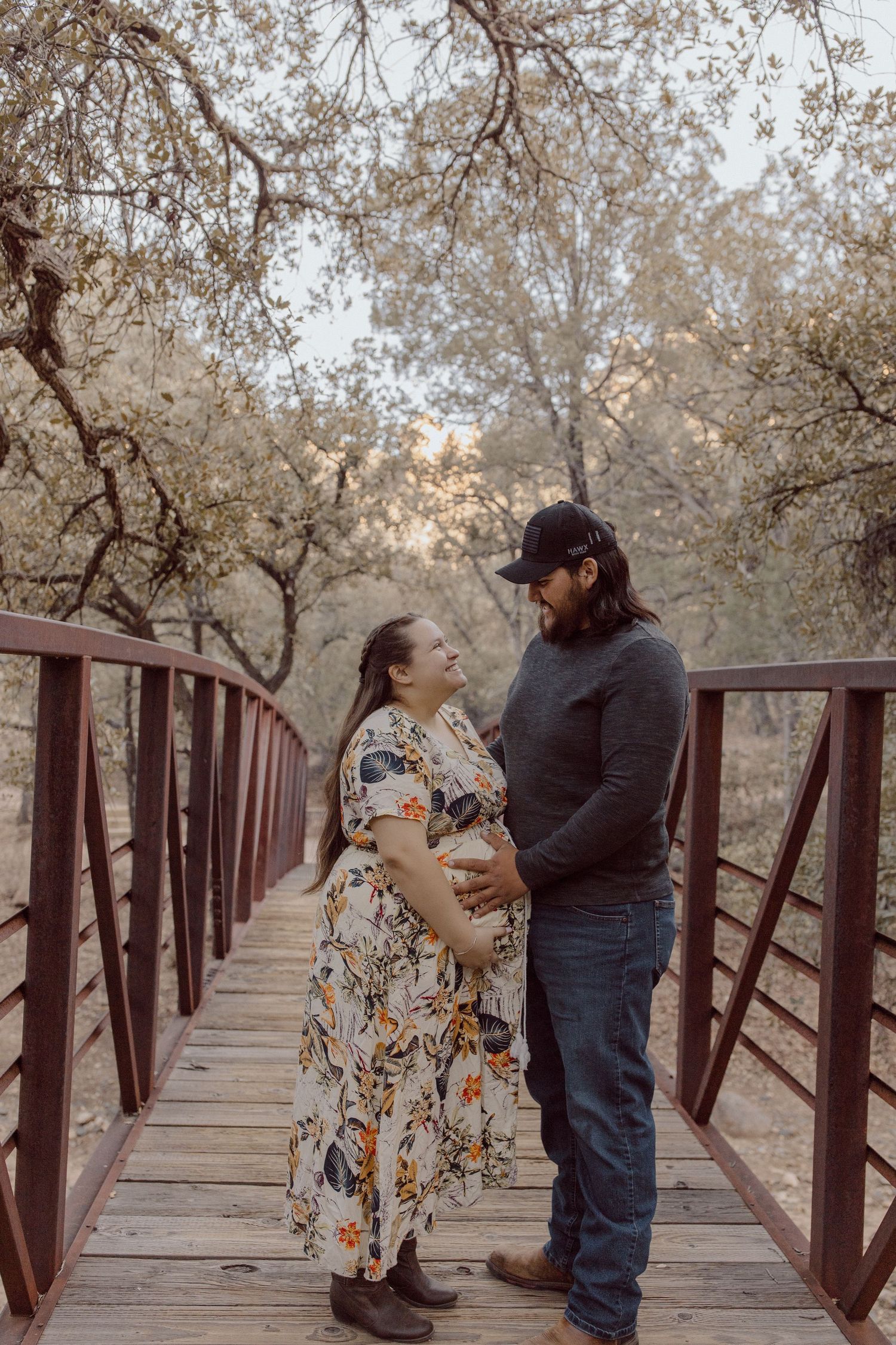 A couple shares intimate moments on a rustic wooden bridge surrounded by autumn trees.