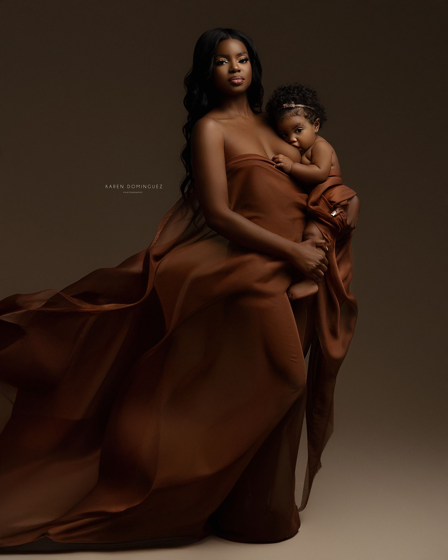 Artistic maternity photos with flowing brown fabric creating elegant movement and curves.