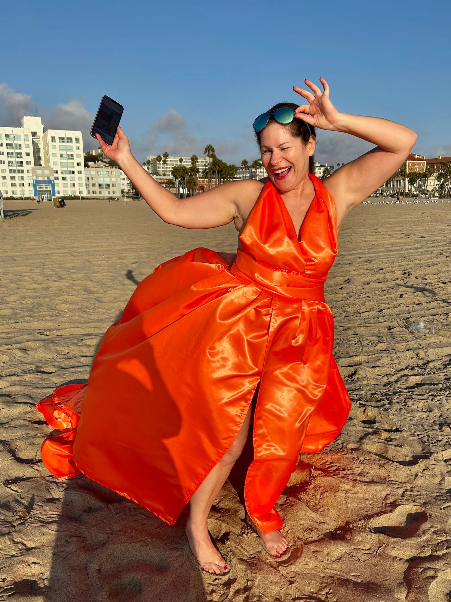 woman holding a smart phone in a flying dress on the beach