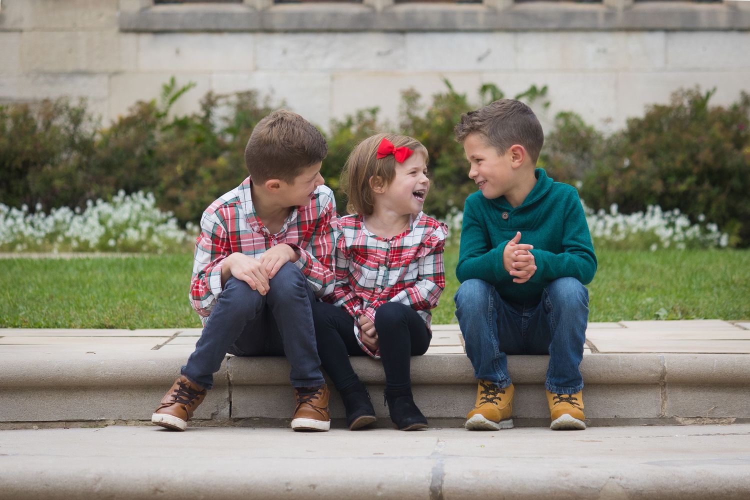 These three kids are excited for the holiday. They sit on stone steps, laugh at each other.