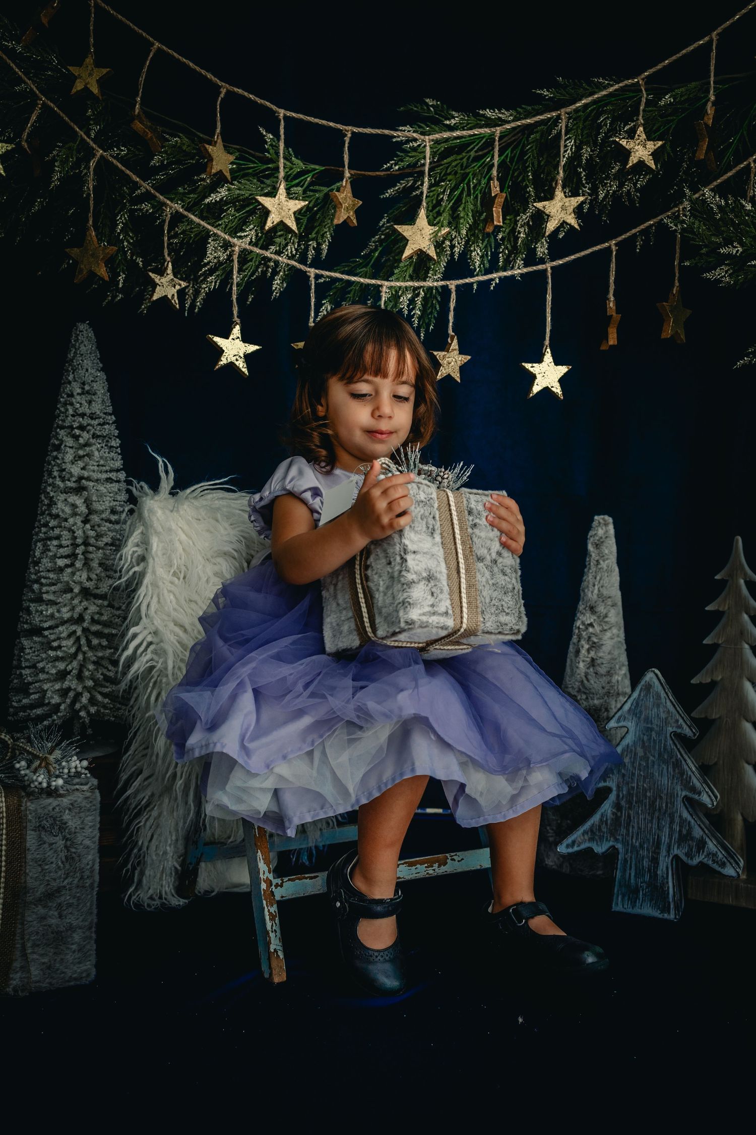 Perfect holiday image of girl anxiously awaiting opening a present.  The image is moody and adorable