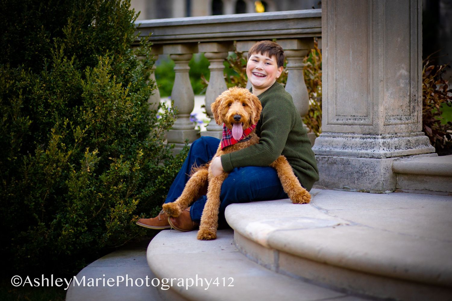 a boy hugs his dog while sitting on stone steps