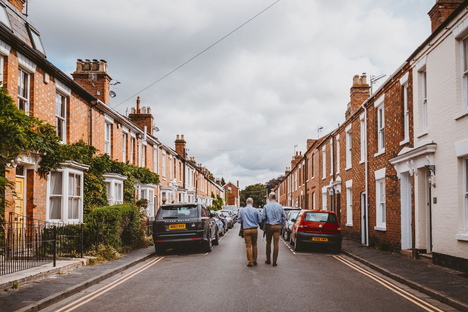 Charming residential street with Victorian style houses and parked cars in England.