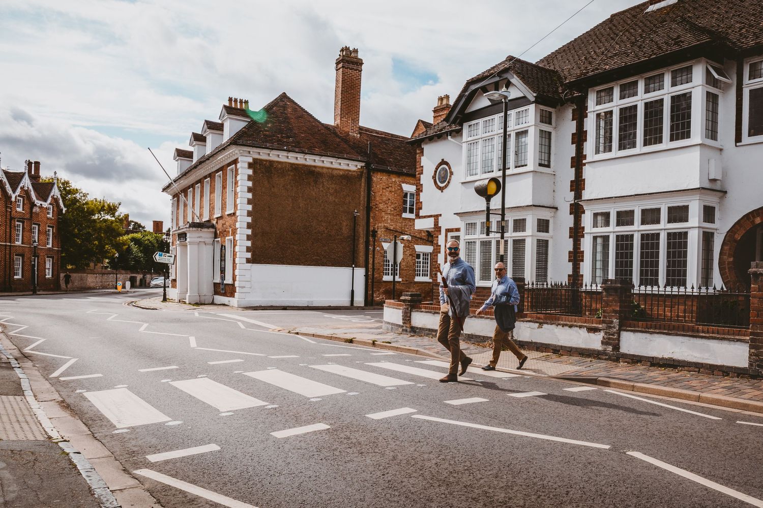 Traditional English suburban street with white and red brick houses and pedestrian crossing.