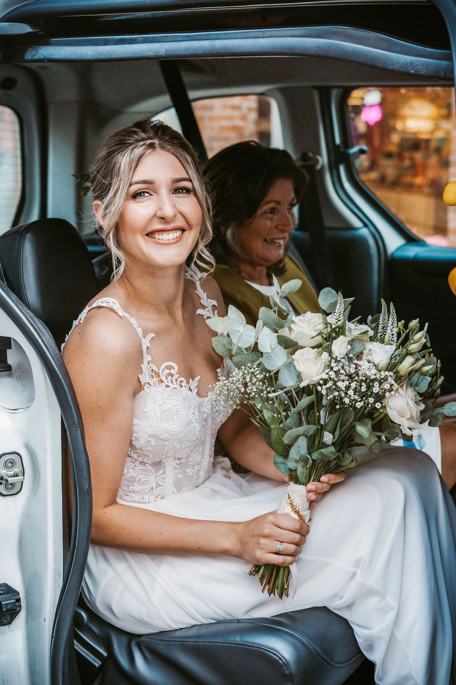 Wedding day transportation showing white floral bouquet in vintage car interior.