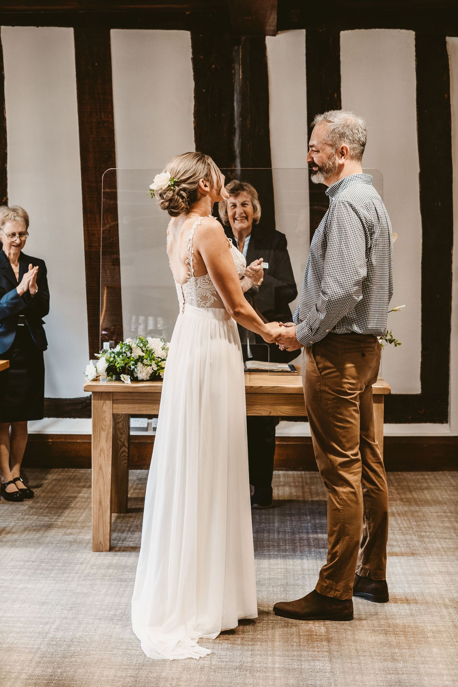 Indoor wedding ceremony in a timber-framed venue with rustic wooden furniture.