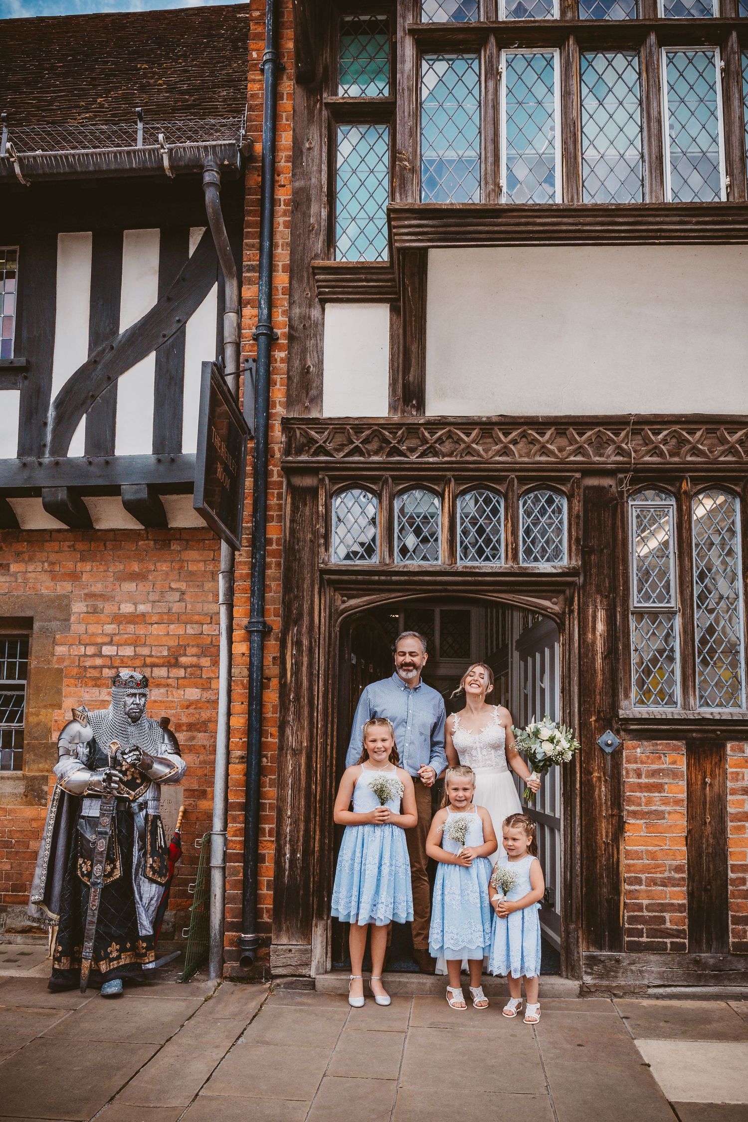 Family portrait in front of historic Tudor-style building with timber framing and leaded windows.