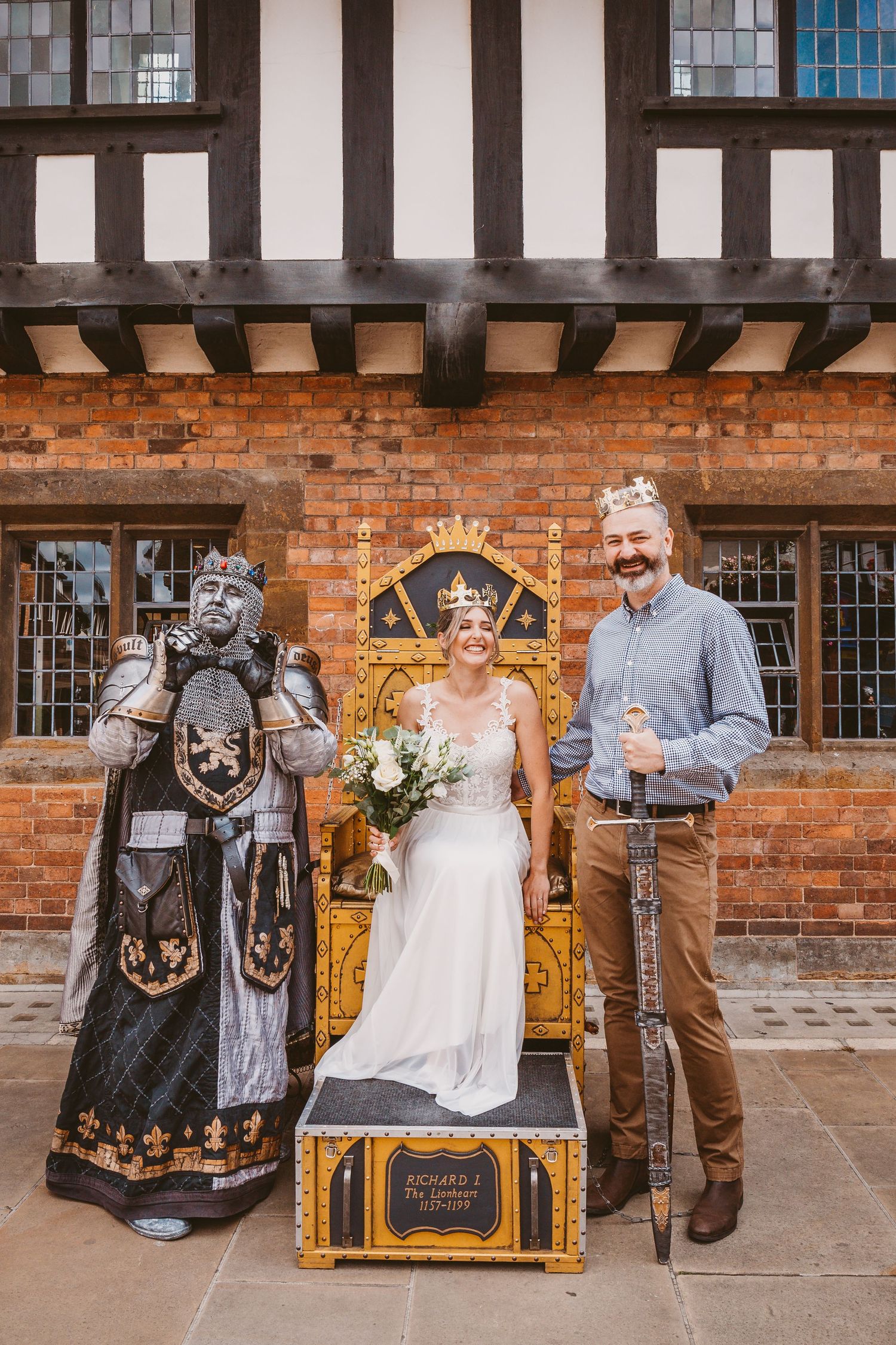 A wedding scene with a bride seated on a golden throne next to a person in medieval costume and formal attire.