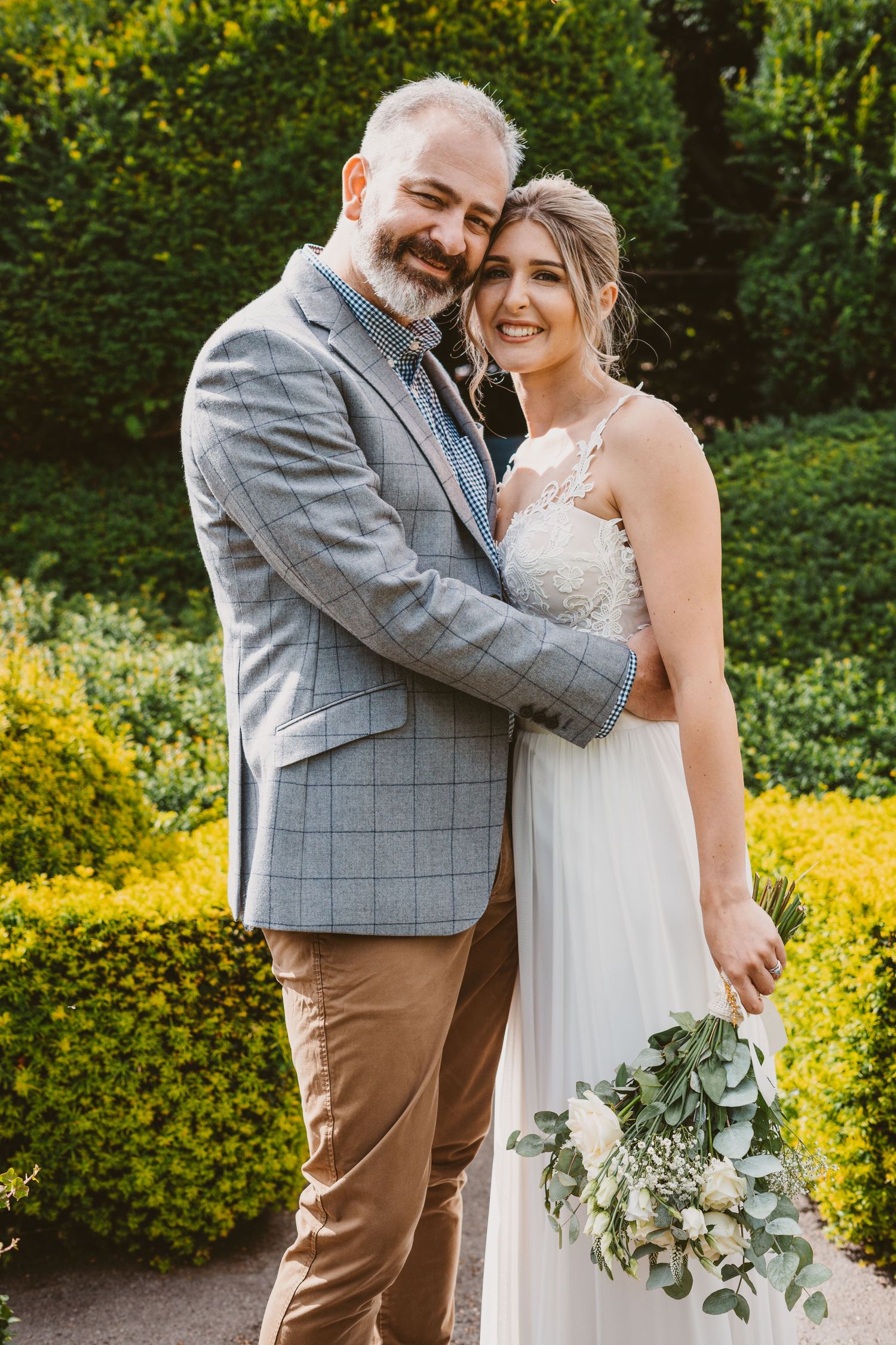 Happy wedding couple sharing intimate moment in lush garden setting.