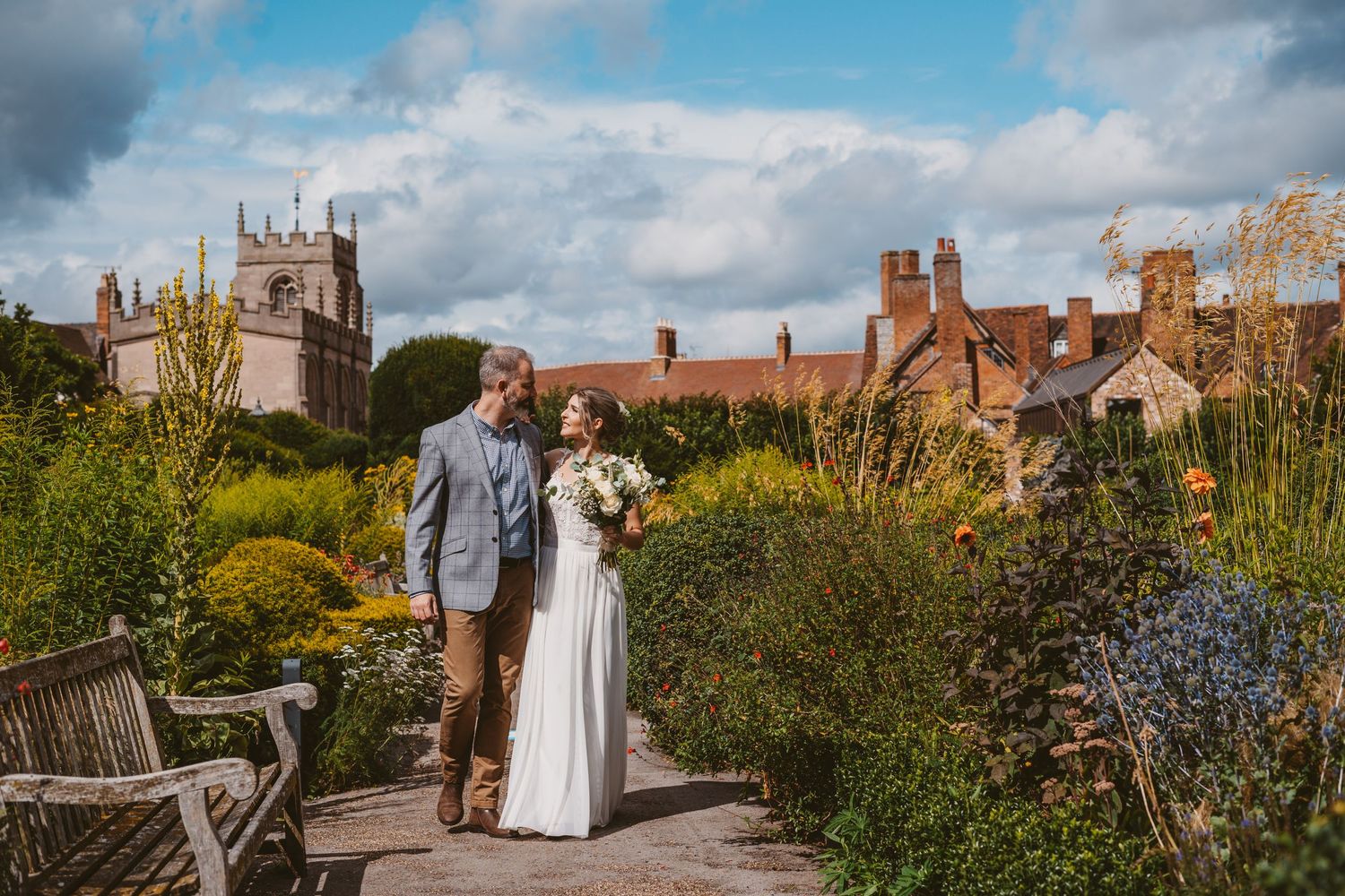 Wedding portrait in traditional English garden with historic architecture and blue skies.