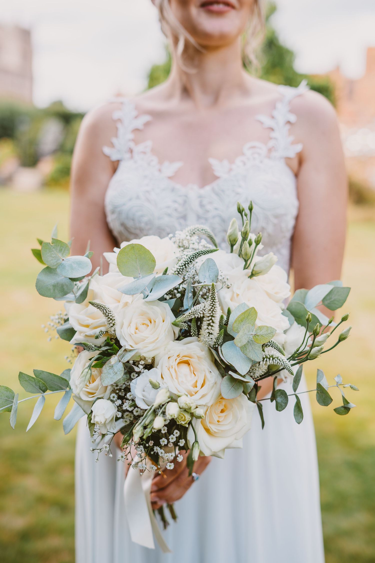 Close-up of white and cream wedding bouquet with roses and eucalyptus leaves.