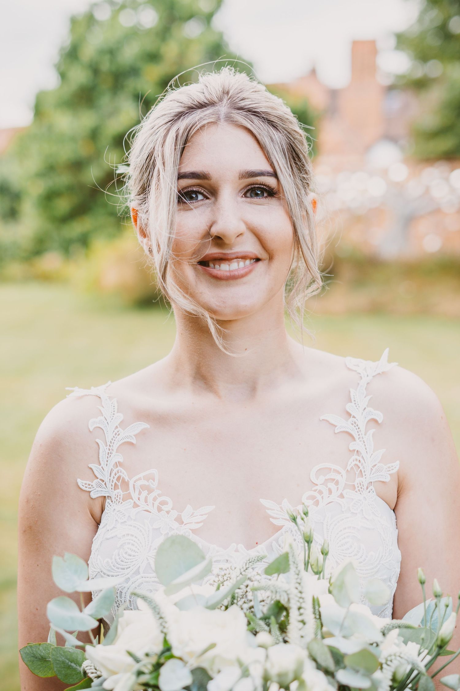 Close up of elegant bridal bouquet with white roses and eucalyptus against garden background.