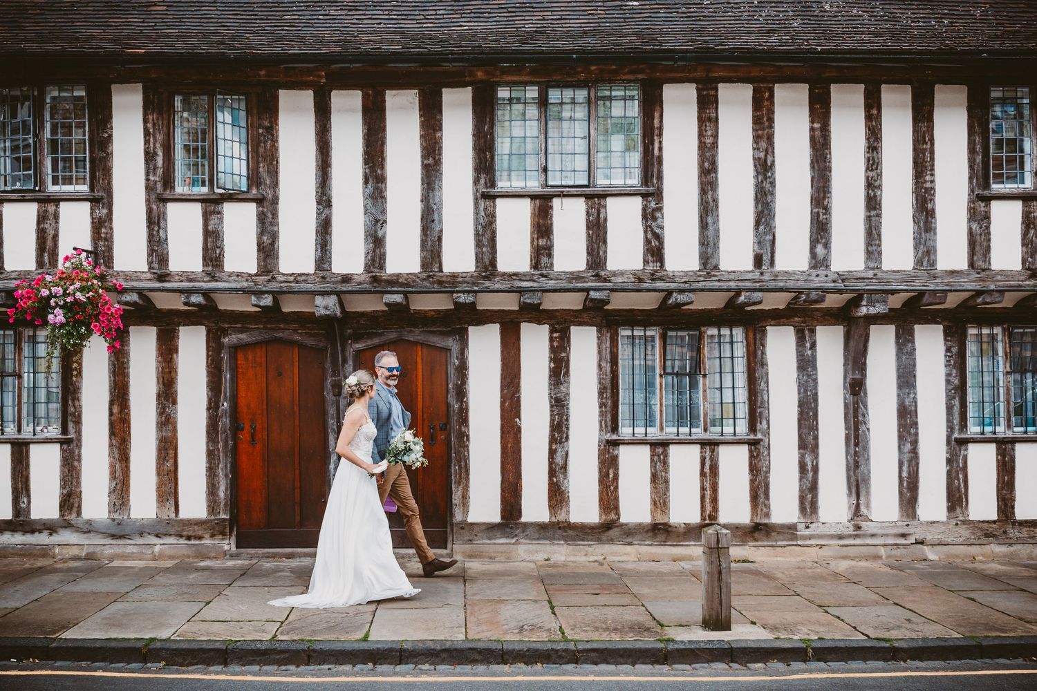 A romantic moment captured outside a traditional Tudor-style building with black and white timber framing.