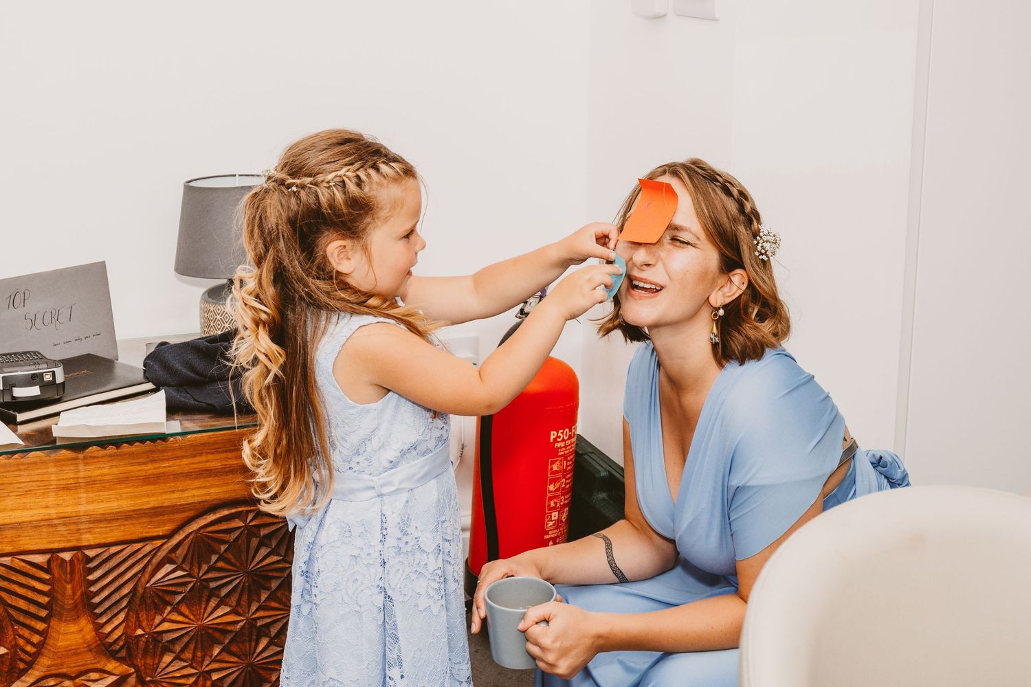Sweet moment of a young girl in blue dress helping with makeup preparations.