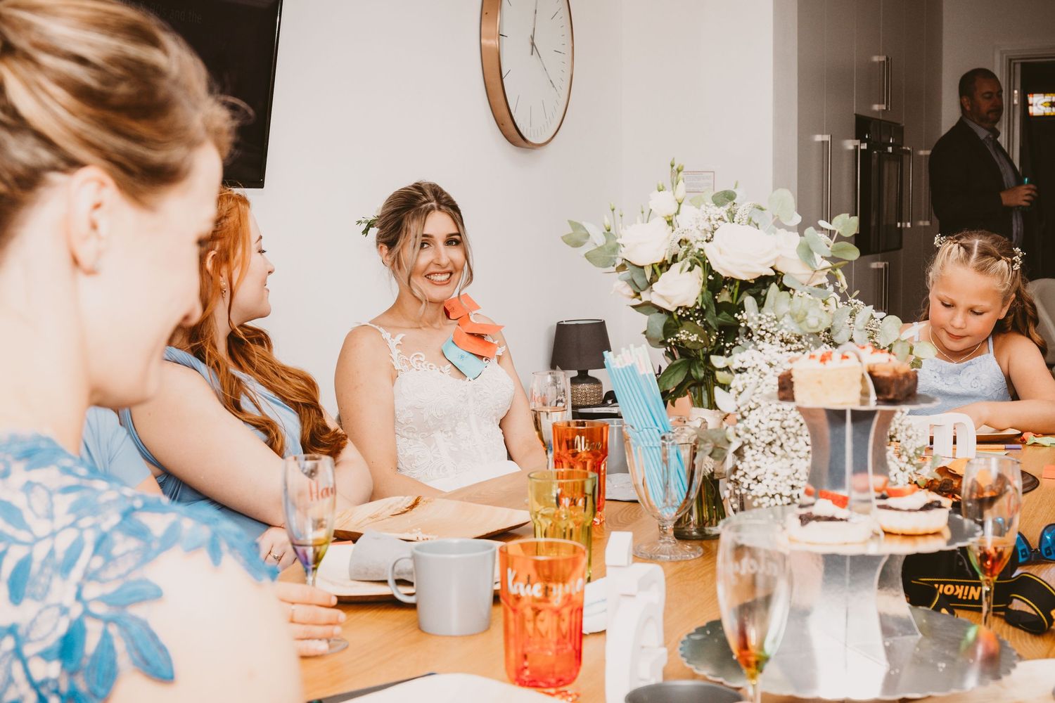 Wedding guests enjoy a celebratory dinner with orange drinks and white floral centerpieces.