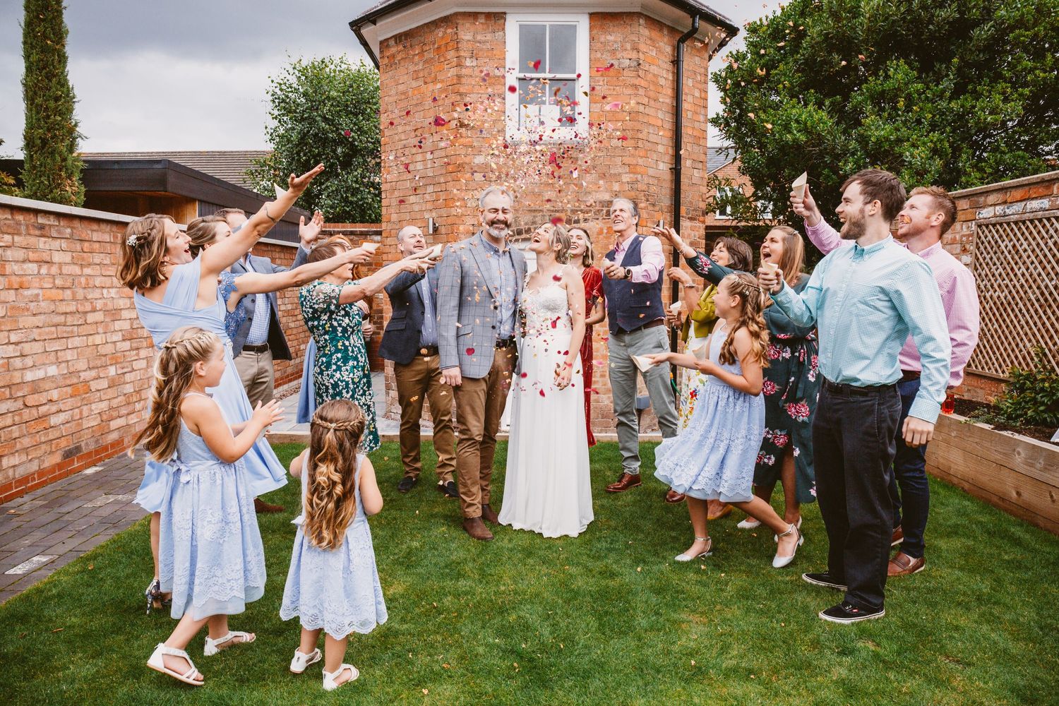 Wedding celebration in a walled garden with guests in blue dresses enjoying the festivities.