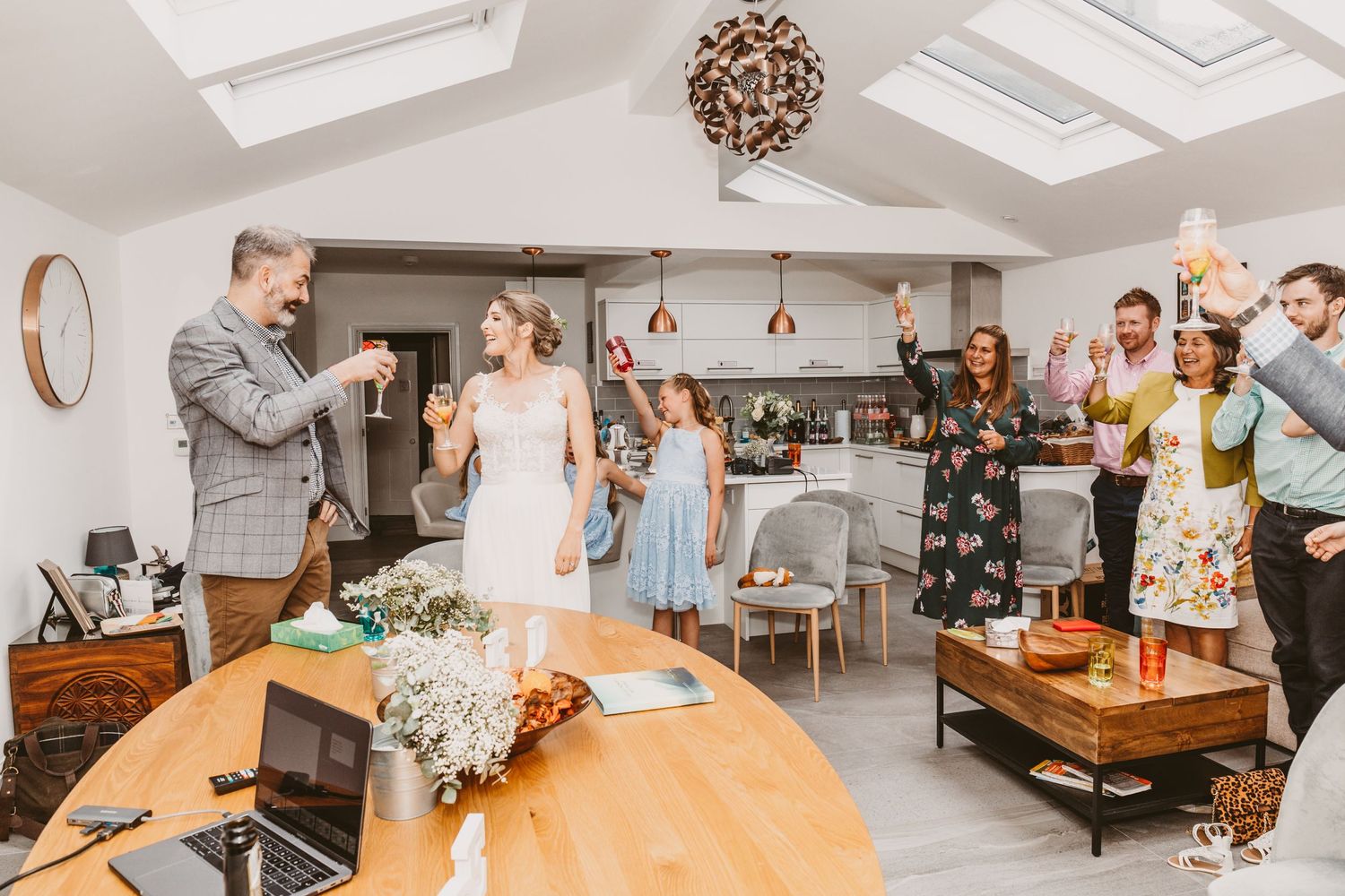 Wedding reception gathering with guests watching a special moment in a modern white room with skylights.