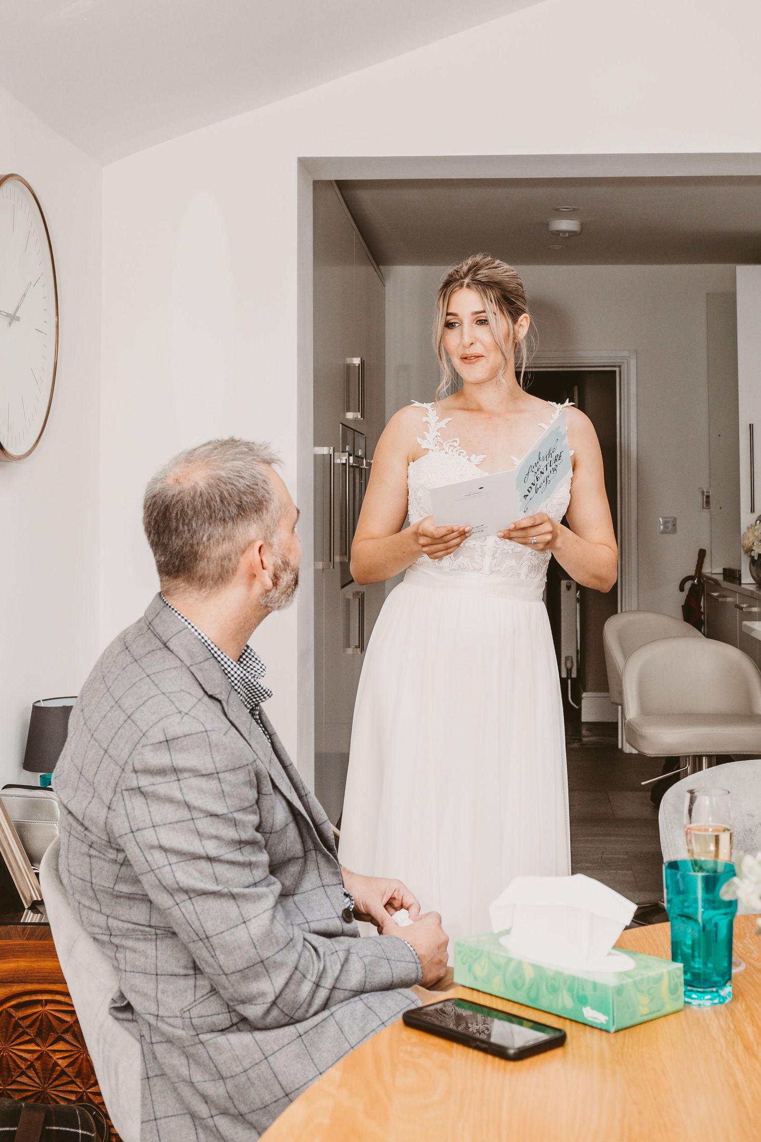 Emotional moment during wedding preparations in modern white interior with light-filled doorway.