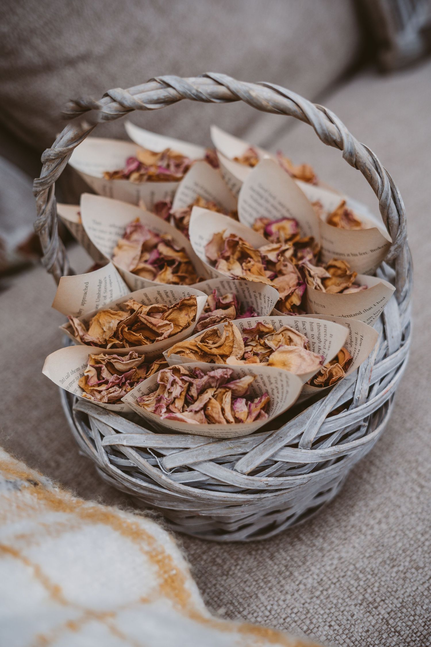 A woven basket filled with dried flower petals and confetti wrapped in paper cones.